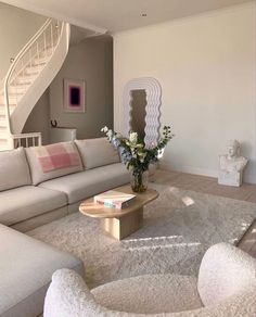 a living room filled with furniture and a spiral staircase in the background on top of a white rug