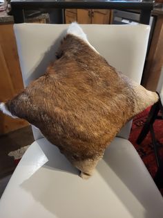 the back end of a white chair with a cow hide on it's seat