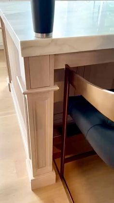 a vase sitting on top of a counter next to a blue seat under a table