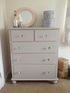 a white dresser sitting in a bedroom next to a mirror and other items on top of it