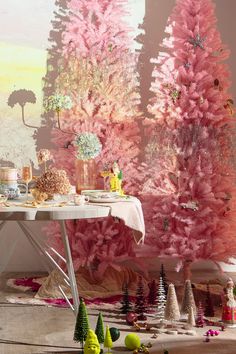 a pink christmas tree is next to a white table with plates and cups on it