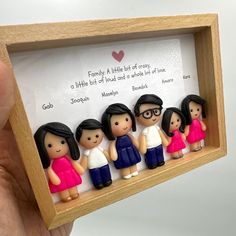 a wooden frame with miniature figurines of people in pink and blue dresses on it