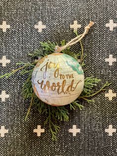 an ornament with the words go to the world on it sitting on a fabric