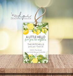 a little hello tag with lemons and leaves on it sitting on a wooden table