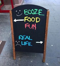 a sign on the sidewalk that says booze food run real life