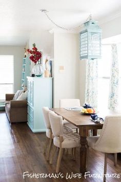 a dining room table with white chairs and a blue refrigerator