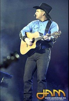 a man with a hat and guitar on stage