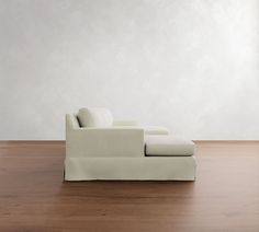 a white couch sitting on top of a wooden floor next to a wall and window