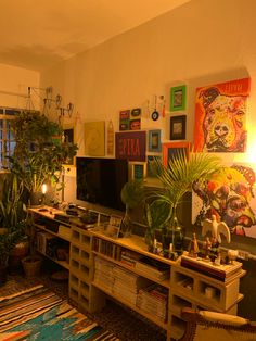 a living room filled with lots of plants and pictures on the wall above it's entertainment center