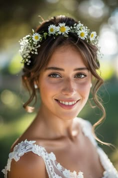 a woman wearing a white dress with daisies in her hair smiling at the camera