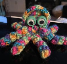 a crocheted octopus with googly eyes sitting on top of a black table