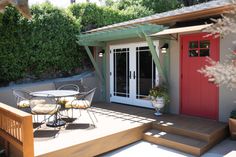 a patio with a table and chairs next to a red door