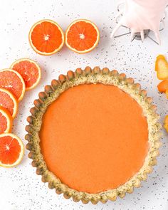 an orange tart is surrounded by slices of grapefruit and tangerines