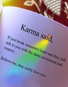 an open book with the words karma said on it's page and rainbow light coming out