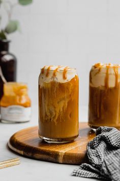 two jars filled with caramel sauce on top of a cutting board