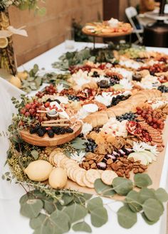 an assortment of food is laid out on a table with greenery and other foods