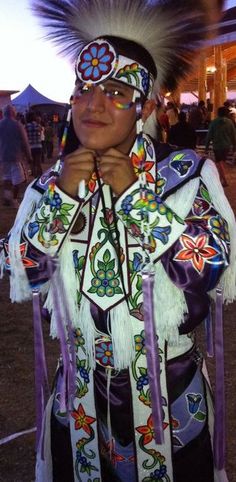 a woman in native american clothing standing with her hands on her chin