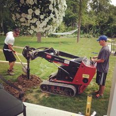 two men are working in the yard with a small machine on it's side