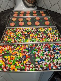 three trays filled with different types of candies on top of a counter next to a stove