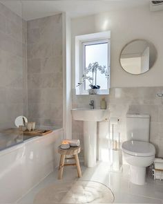 a white bathroom with a toilet, sink and bathtub in the middle of it