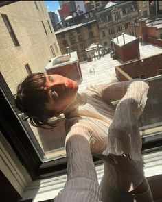 a woman laying on top of a window sill in front of a cityscape