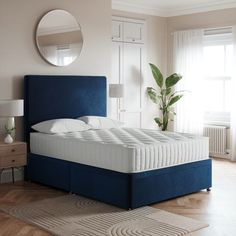 a blue bed frame in a bedroom with white walls and wooden floors, along with a round mirror on the wall