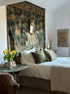 a bedroom with a large tapestry hanging over the headboard and pillows on the bed