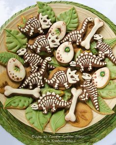 decorated sugar cookies in the shape of dogs and bones on a plate with green leaves