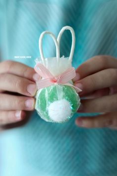 a person holding an ornament shaped like a bunny with a bow on it's head