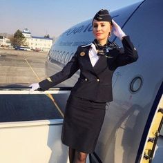 a woman in uniform standing next to an airplane