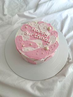 a pink and white birthday cake on a plate