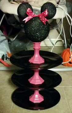 a minnie mouse cake sitting on top of a black plate in front of a chair