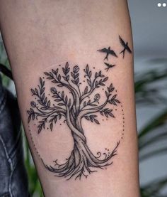 a tree tattoo on the arm with birds flying around it