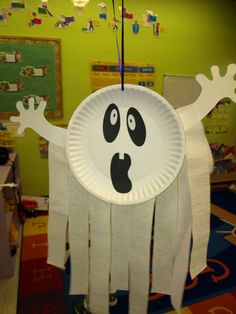 a paper plate with a ghost on it in the middle of a classroom area,