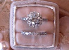 three diamond rings in a ring box on a lace tablecloth with pearls and beads