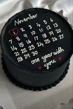 a black cake with white frosting and red hearts on the top that says, november