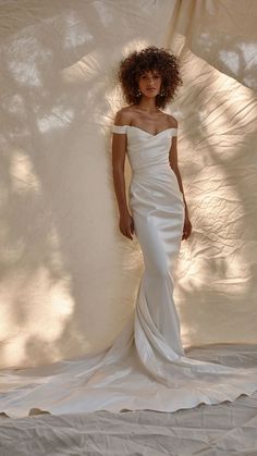 a woman in a white wedding dress posing for a photo with her hands on her hips