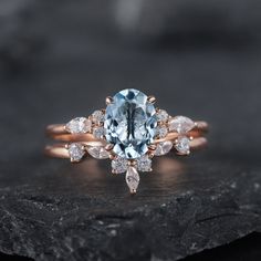 a blue and white diamond ring sitting on top of a black piece of rock with diamonds around it