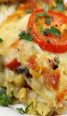 a slice of vegetable lasagna on a white plate with tomatoes and parsley