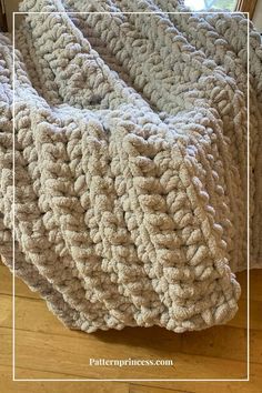 a crocheted blanket sitting on top of a wooden floor next to a window