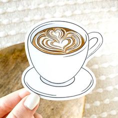 a hand holding up a paper cutout of a cup of coffee