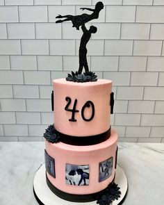 a pink cake with black decorations and a silhouette of a woman on top that reads forty