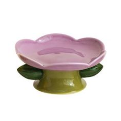 a pink flower shaped bowl sitting on top of a green base