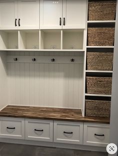 a white mud room with lots of drawers and baskets