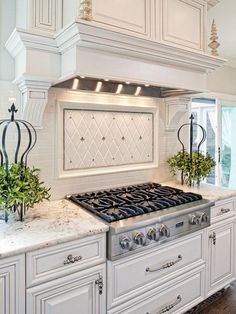 a stove top oven sitting inside of a kitchen next to white cabinets and counter tops