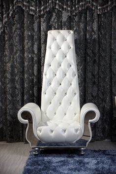 a white chair sitting in front of a black curtain