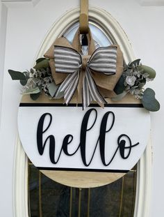 a door hanger with the word hello written on it and a bow hanging from the front