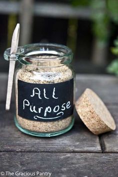 a jar filled with sand sitting on top of a wooden table next to a spoon