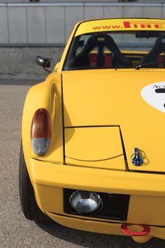 the front end of a yellow sports car with stickers on it's hood