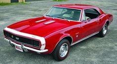 a red muscle car parked in a parking lot